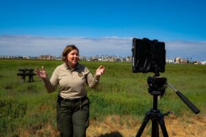 State Park Interpreter standing in front of tablet on tripod with salt marsh behind her.