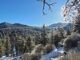 Mountains in the far background with clear blue skies and pine trees surrounding the area with snow covering the ground.